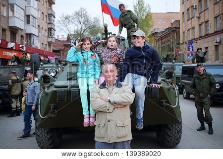 SAMARA - MAY, 6, 2015: Boy, man and two girls (with model releases) pose on armored vehicle in Samara during military celebration. Red Square is not affected by military equipment on parade May 9th