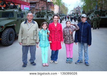 SAMARA - MAY, 6, 2015: Boy, man, woman and two girls (with model releases) pose near armored vehicles during military celebration. Red Square is not affected by military equipment on parade May 9th