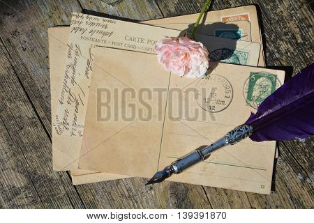 old blank vintage postcard with old stamp is on old wood with pink rose and nib