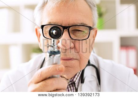 Otolaryngologist specialist looking through otoscope, healthcare concept