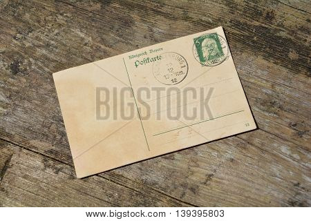 old blank vintage postcard with old stamp is on old wood