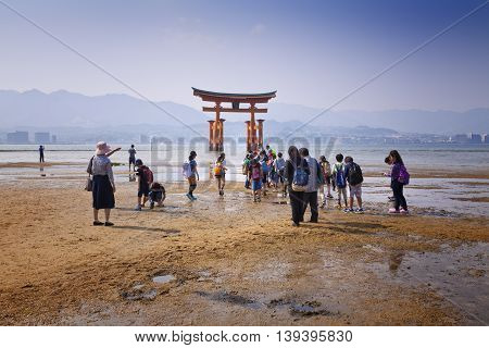 MIYAJIMA, JAPAN - MAY 27: Tourists walk around the famous floating torii gate of the Itsukushima Shrine on Miyajima at sunset on May 27,2016 in Miyajima, Japan