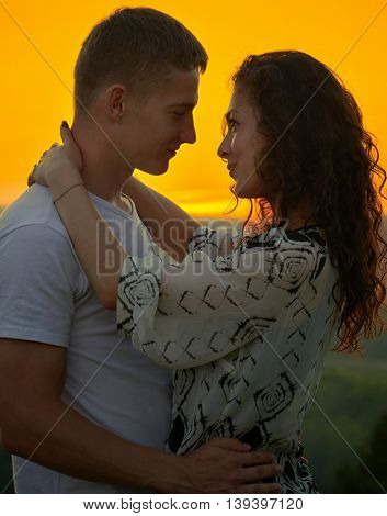 romantic couple at sunset on bright yellow sky background, love tenderness concept, young adult people