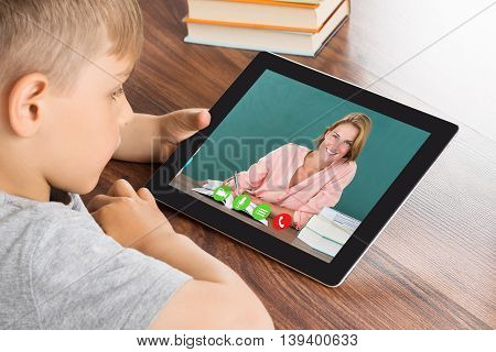 Close-up Of Cute Little Boy Videoconferencing On Digital Tablet In Classroom