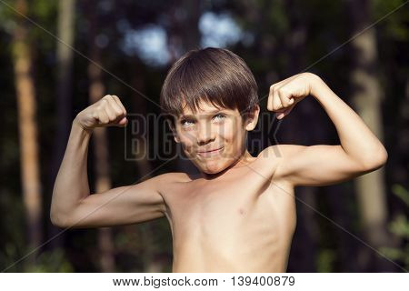 portrait of a boy in nature which shows his muscles