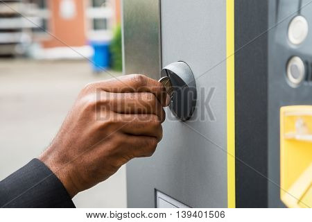 Close-up Of Person's Hand Inserting Coin Into Parking Meter