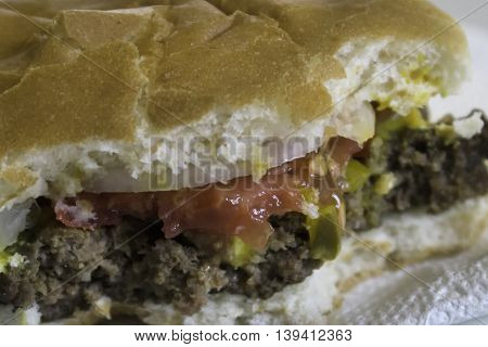 A hamburger sandwish with all the fixings that has been sampled.