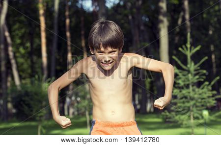 portrait of a boy in nature which shows his muscles