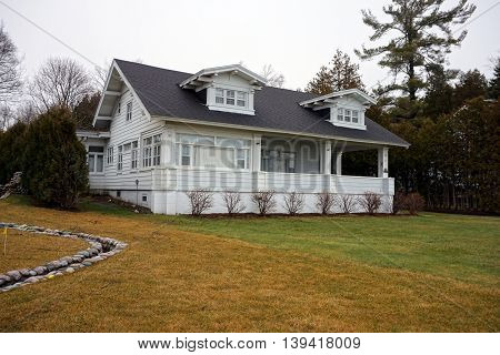 WEQUENTONSING, MICHIGAN / UNITED STATES - DECEMBER 22, 2015: A white home with a front porch on Beach Drive in Wequetonsing, Michigan.