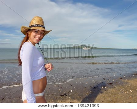 Smiley New Zealand girl on the beach in Auckland. Takapuna beach and Rangitoto island in background.