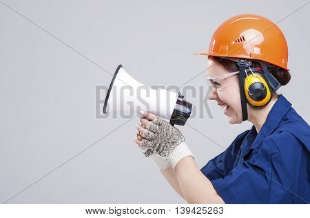 Professions Concepts.Portrait of Expressive Caucasian Female With Loudspeaker Horn Posing In Hardhat Against White. Equipped with Coverall. Horizontal Image