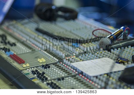 Professional Mixing Console Closeup During Work Time. Microphone and Headphones on Surface. Horizontal Image