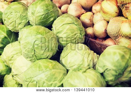 sale, harvest, food, vegetables and agriculture concept - close up of cabbage and onion at street market