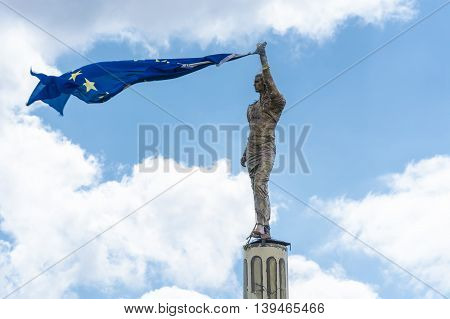 Antike stone statue holds a European flag in his hand.