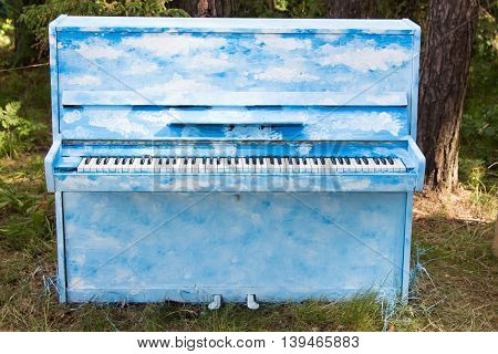 blue piano standing on the ground in the forest