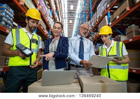 Businessmen and warehouse workers in warehouse