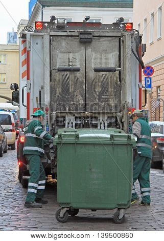 Warsaw, Poland - October 23, 2015:service workers is loading trash from dustbin to garbage truck outdoot in Warsaw, Poland