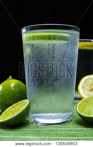 Glass with cold sparkling mineral water with fresh green lime seltzer
