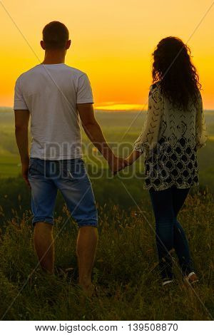 young couple at sunset on sky background, love concept, romantic people