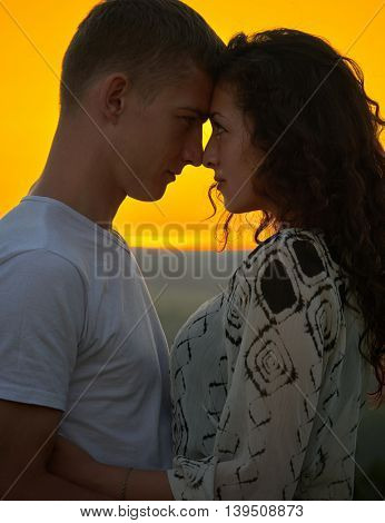 romantic couple at sunset on bright yellow sky background, love tenderness concept, young adult people