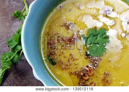 Yellow Lentil soup or Arhar Daal fry with the tadka of cumin seeds garlic and green chilies on a moody background