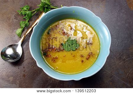 Overhead view of yellow Lentil soup or Arhar Daal fry with the tadka of cumin seeds garlic and green chilies on a moody background with copy space