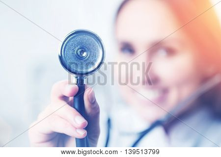 Smiling doctor holding phonendoscope blurred look. Concept of medical help.Film effect