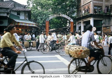 GUANGZHOU / CHINA - CIRCA 1987: People ride bicycles past the entrance to Guangzhou's Qingping Market.