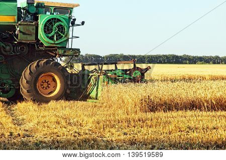 The photo of Combine harvester working in wheat field.