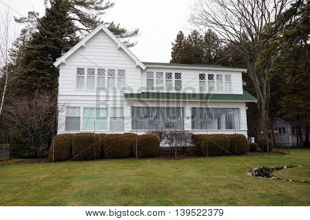 WEQUENTONSING, MICHIGAN / UNITED STATES - DECEMBER 23, 2015: The front porch of a white home, on Beach Drive in Wequetonsing, is protected from the winter weather.