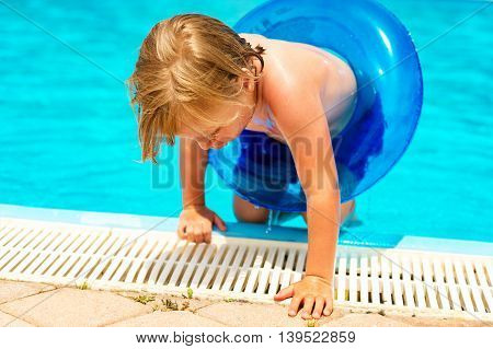 Happy little boy playing in swimming pool on a hot summer day