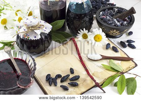 Cooking still life with jam jars, berries, cook book and sugar in spoon on the table