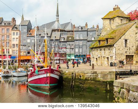 HONFLEUR FRANCE - MAY 6, 2014: Old boat and medieval Lieutenancy building - entrance to the old harbour. Honfleur, Normandy, France