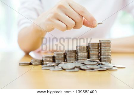 Close-up Of woman Hand Put Coins To Stack Of Coins