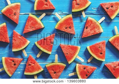 Watermelon slice popsicles on a blue rustic wood background Popular summer fruit with yummy watermelon
