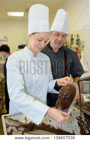 commis chef prepares chocolate with chef checking