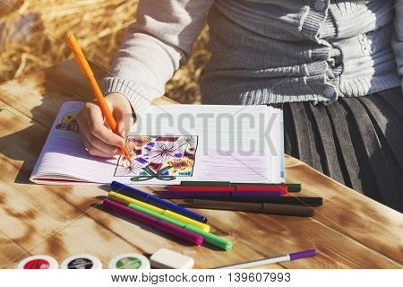 The girl draws the patterns with a Sharpie on the album. Front view