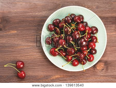 Plate of ripe cherries on a wooden rustic table