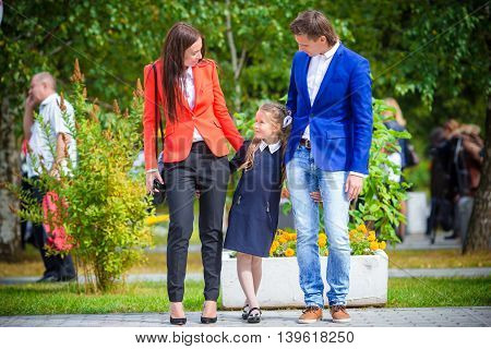 Mother and father brings little daughter to school.