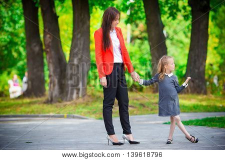 Mother brings her little daughter to school.