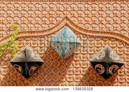 XinjiangChina 09/05/2015 Three traditional Chinese dopa hats attached to an orange wall with decorations throwing a shadow on a sunny day