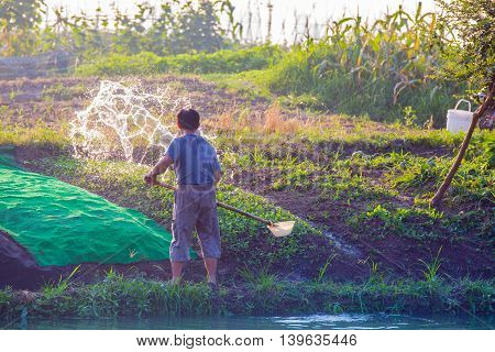 Shanghai China 07/22/2016 Poor Chinese farmer is watering his fields with a self made ladle from a nearby river in Shanghai