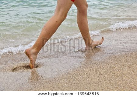 feet of boy running along the beach in the water