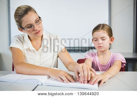 Teacher assisting blind student in library at school