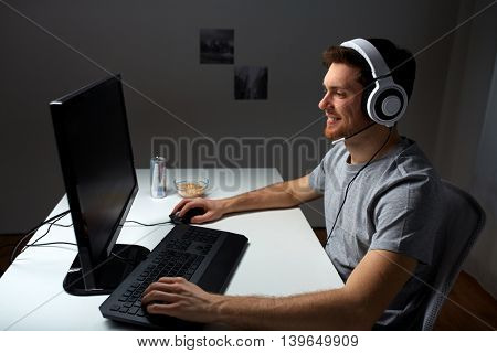 technology, gaming, entertainment, let's play and people concept - happy young man in headset with pc computer playing game at home and streaming playthrough or walkthrough video