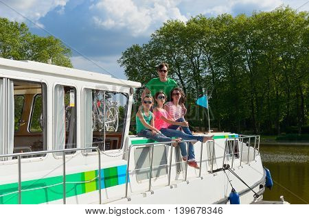 Family vacation, travel on barge boat in canal, happy parents with kids having fun on river cruise in houseboat