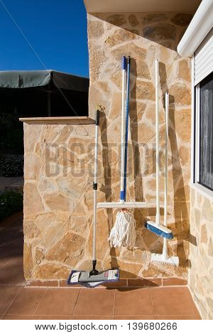 Cleaning equipment hanging on stone wall in the sun Mallorca Balearic islands Spain.
