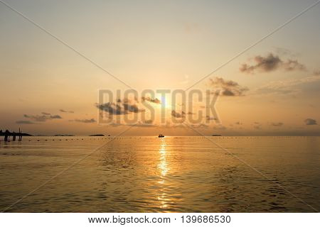 Seascape of sea during sunrise with silhouette of small boat at Ao Lung Dam beach in Samet island Thailand.