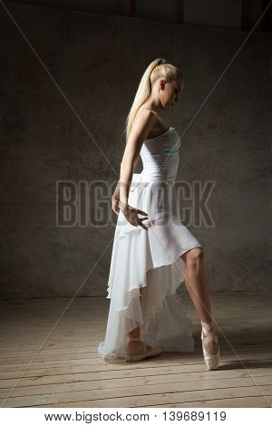 Side view of beautiful blonde ballet dancer with hair in tail posing in studio