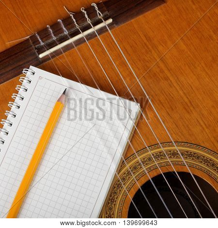 Musical instruments - the Acoustic guitar and a notebook with a pencil.